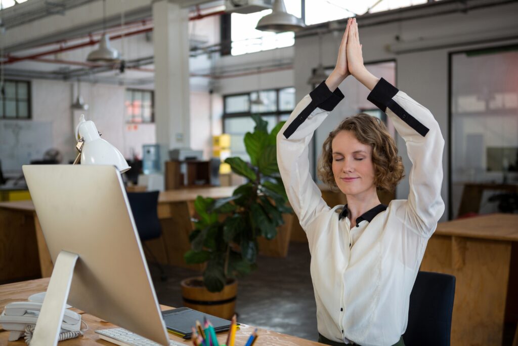 Junge Frau praktiziert Yoga im Büro.
